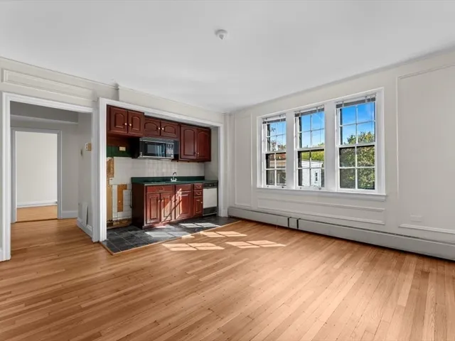 a view of an empty room with wooden floor fireplace and a window