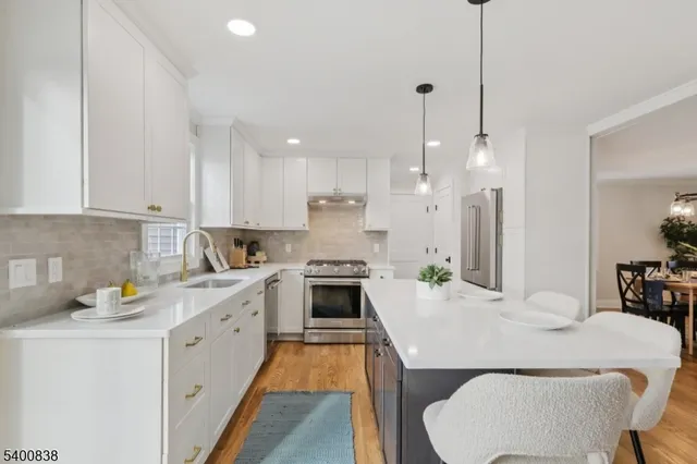 a kitchen with a white center island a sink stainless steel appliances and cabinets