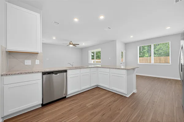 a kitchen with granite countertop white cabinets and wooden floor