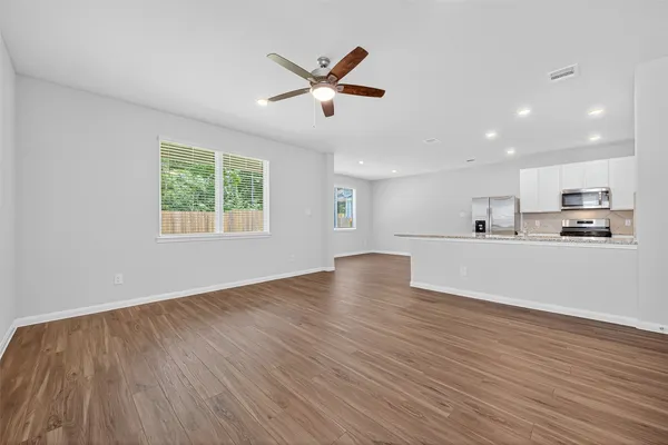 a view of an empty room with wooden floor and a window