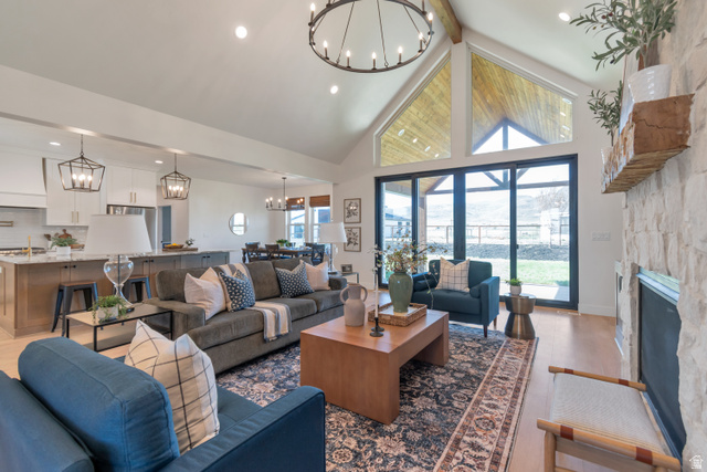 1820 West Farmhouse Flats Road Peoa, UT 84061 - Photo 11 of 79 Vaulted ceiling with exposed beam, large-format sliding glass doors, white stone fireplace, and light wood-finish flooring