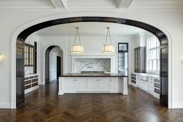 an empty room with wooden floor a kitchen view and a fireplace