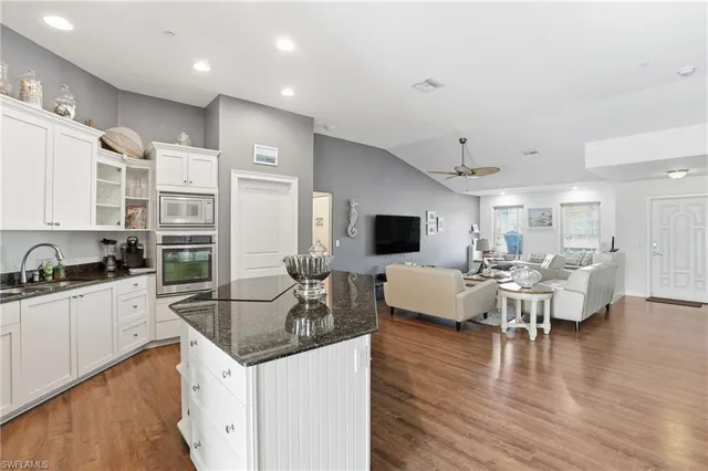 a living room with furniture kitchen view and a wooden floor