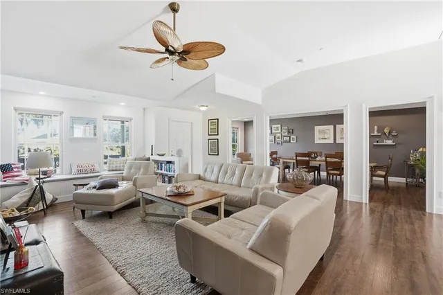 a living room with furniture kitchen view and a wooden floor