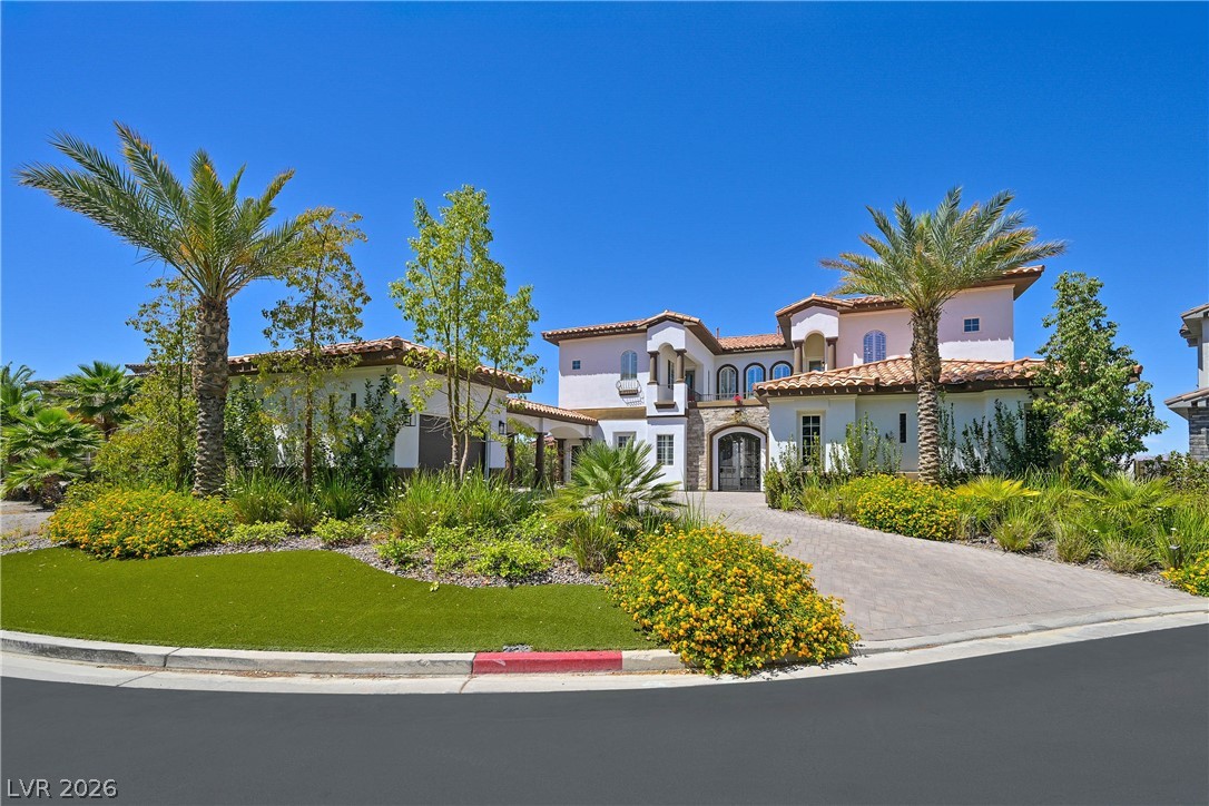 6 Rue Du Ville Henderson, NV 89011 - Photo 87 of 99 This Mediterranean-inspired home boasts an inviting entrance and lush, manicured landscaping under a clear sky.