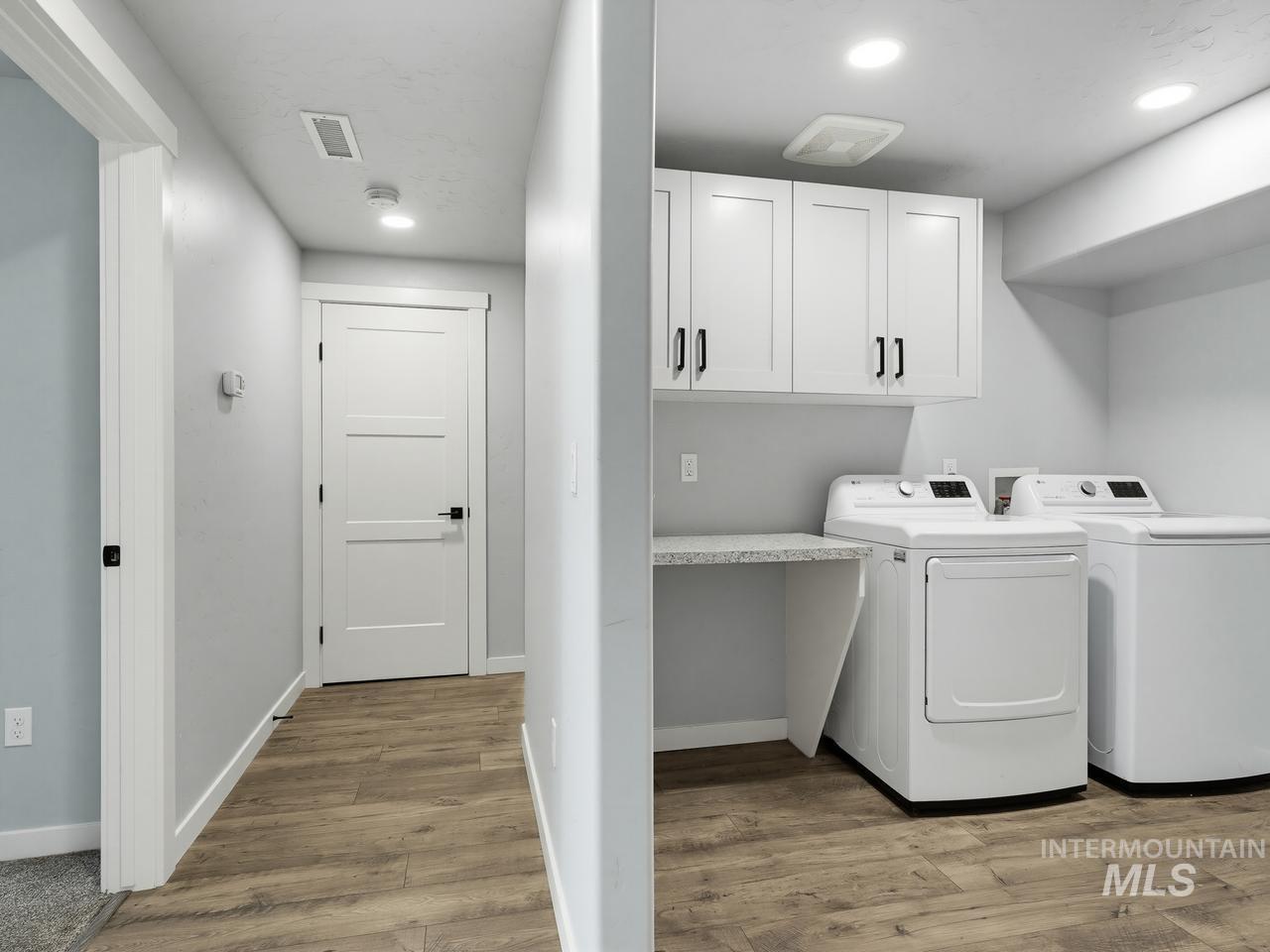 4950 West Columbia Road Nampa, ID 83687 - Photo 33 of 50 Dedicated laundry area featuring white shaker-style cabinetry with matte black hardware, a grey speckled countertop, and wood-finish flooring