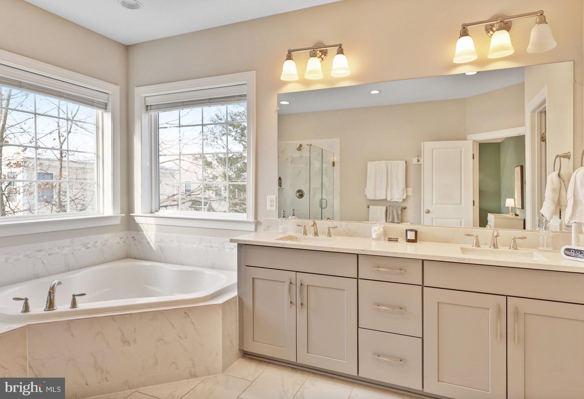 8028 Wellington Road Alexandria, VA 22308 - Photo 25 of 43 a bathroom with a tub a sink double vanity window and mirror