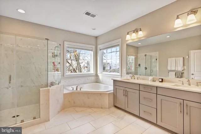 a spacious bathroom with a double vanity sink a mirror and a bathtub