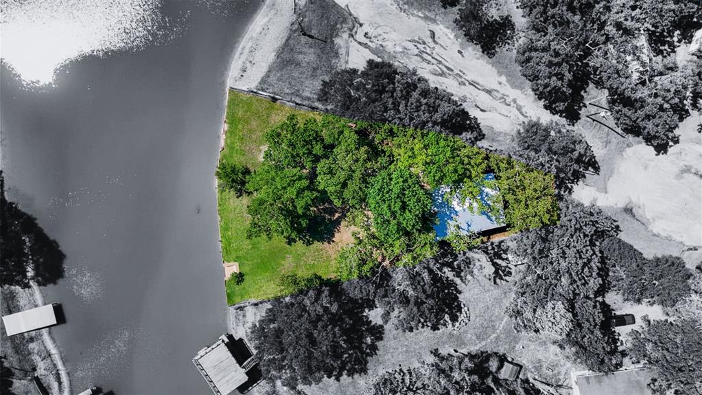 7110 Apache Circle Mabank, TX 75156 - Photo 2 of 39 Waterfront property featuring a private boat dock, expansive green lawn, mature trees, and a secluded residence with a blue roof