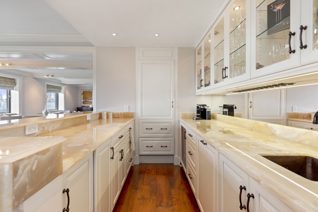 160 Central Park South, Unit 1201 Manhattan, NY 10019 - Photo 10 of 20 a large white kitchen with a lot of counter space and wooden floor