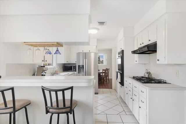 a kitchen with stainless steel appliances a sink a stove a table and chairs
