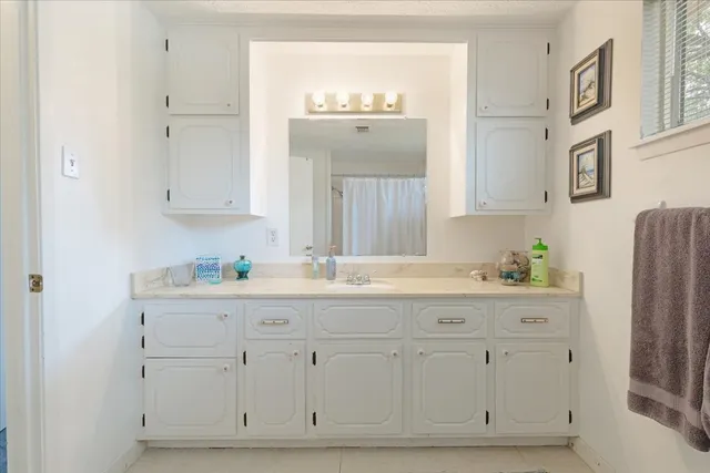 a bathroom with white cabinets and a sink