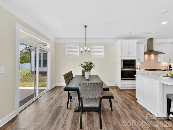 a dining room with furniture wooden floor a rug a potted plant a fireplace and a chandelier