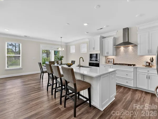 a kitchen with stainless steel appliances a table chairs stove and cabinets