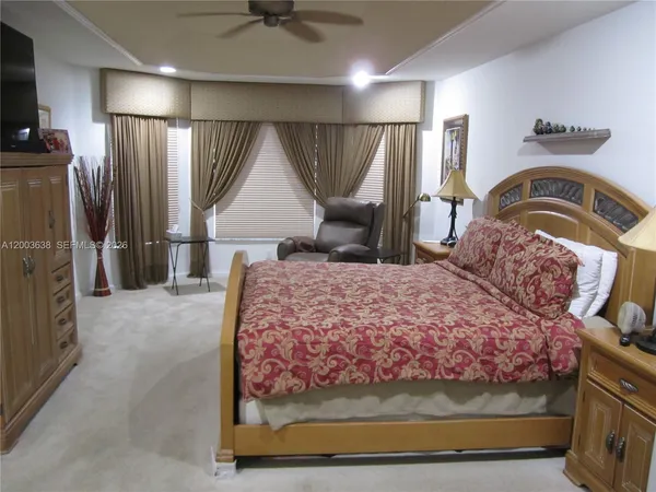 a bedroom with a bed a mirror on dresser and a chandelier