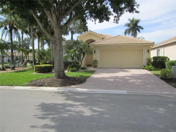 a view of a house with a yard and palm trees
