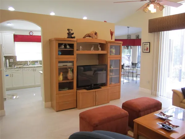 a living room with furniture a flat screen tv and floor to ceiling window