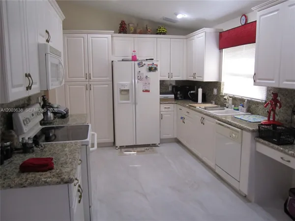 a kitchen with white cabinets and refrigerator