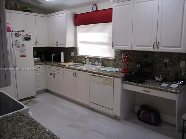 a kitchen with stainless steel appliances granite countertop a sink a stove a refrigerator and cabinets