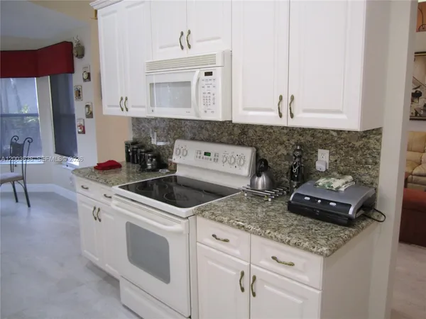 a kitchen with granite countertop a sink stove and cabinets