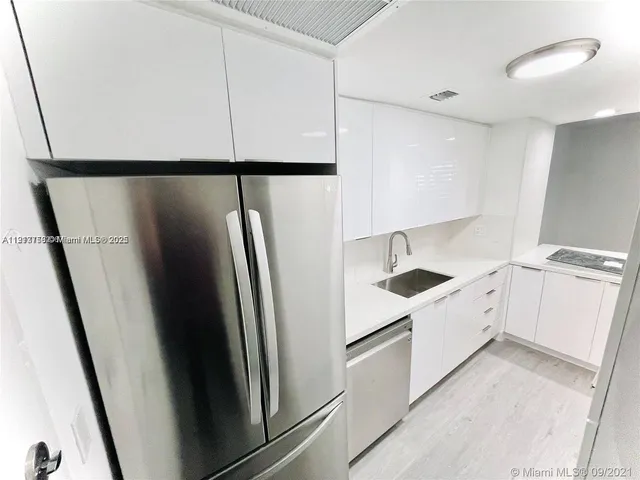 a kitchen with stainless steel appliances a refrigerator a sink and white cabinets