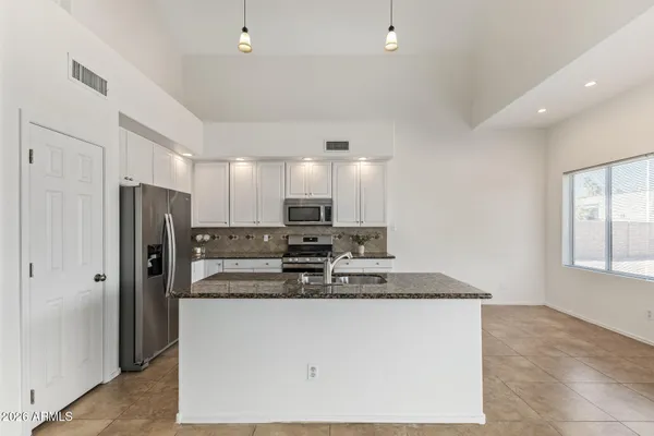 an empty room with wooden floor chandelier fan and windows