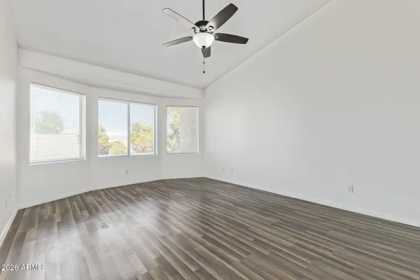 an empty room with wooden floor chandelier fan and windows
