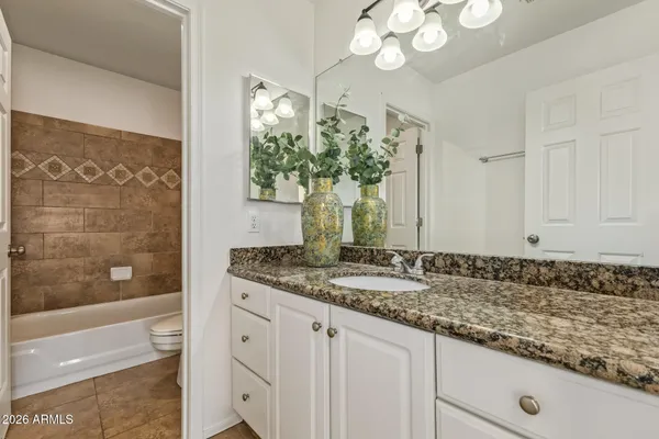an empty room with wooden floor chandelier fan and windows