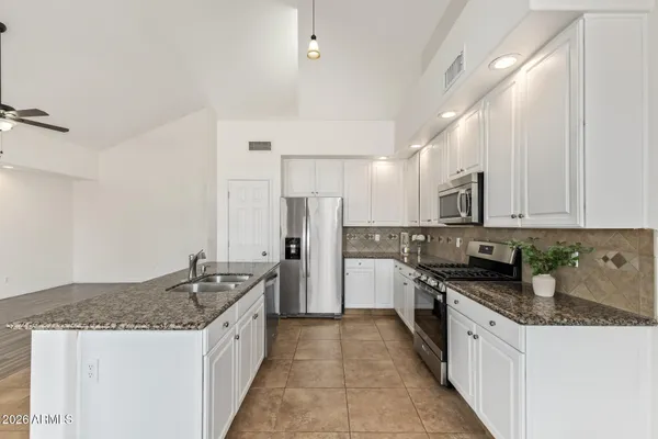 a large kitchen with stainless steel appliances granite countertop a sink stove and refrigerator