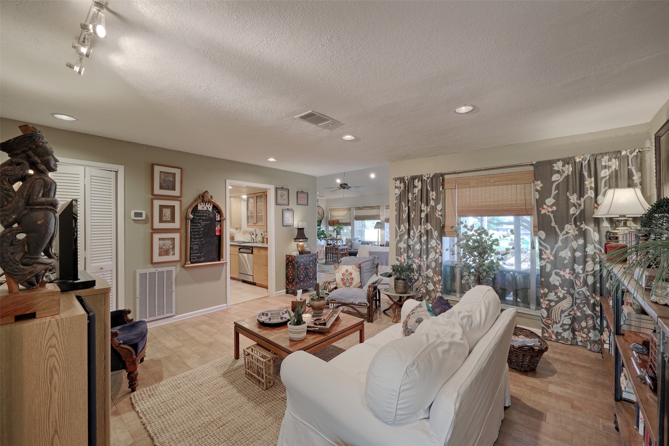 34 April Hill Conroe, TX 77356 - Photo 5 of 33 Enter the home into a bright and large living room. Large windows overlook the back porch and light colored laminate flooring adds to the brightness of the space. The kitchen and a family room are beyond.