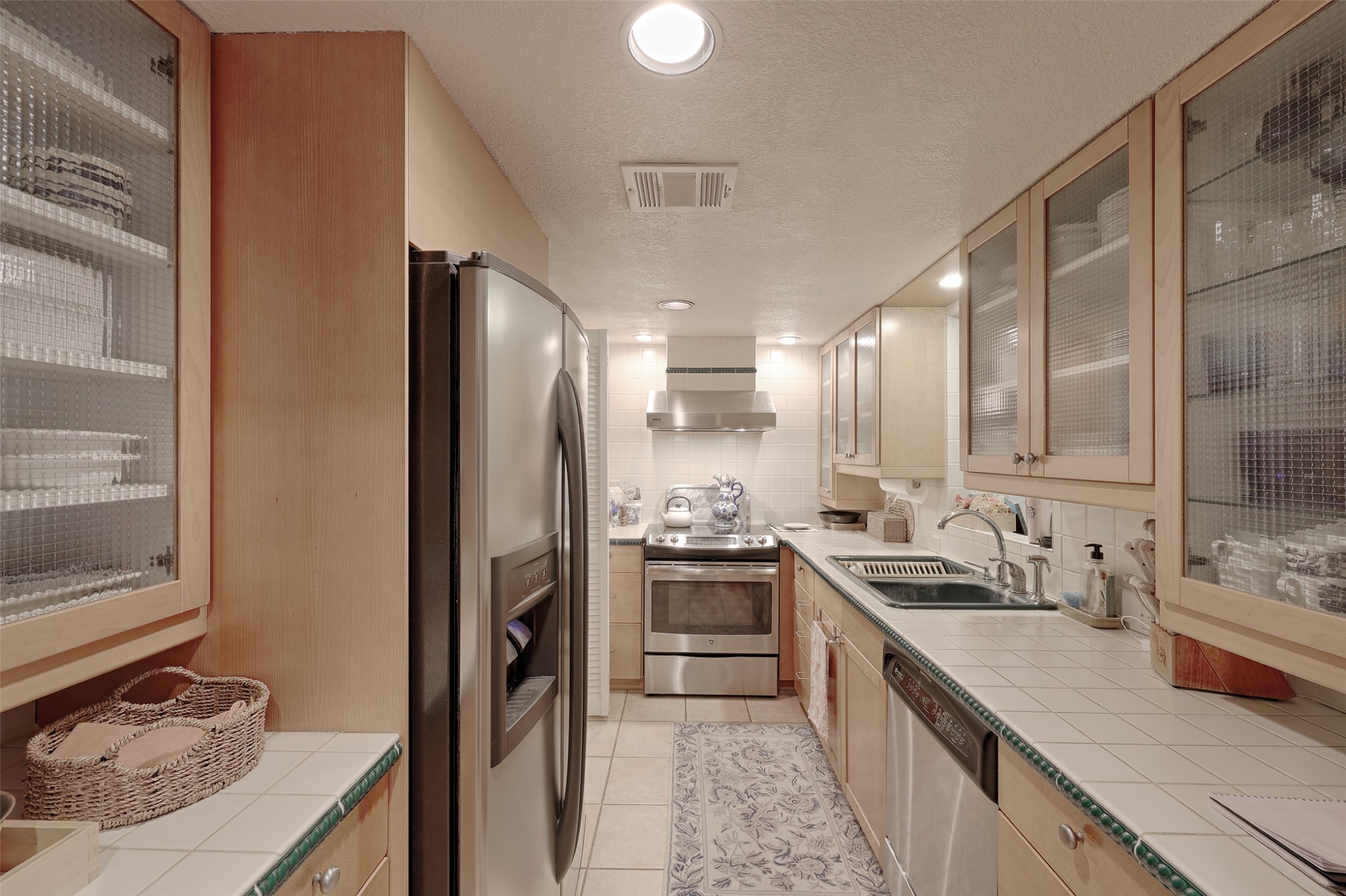 34 April Hill Conroe, TX 77356 - Photo 9 of 33 The galley kitchen is efficient and bright. With glass upper cabinets, the space feels open.
