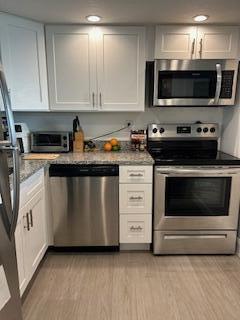 400 Wilma Circle, Unit 208 Riviera Beach, FL 33404 - Photo 5 of 28 a kitchen with stainless steel appliances a stove a microwave sink and cabinets
