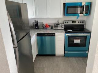 400 Wilma Circle, Unit 208 Riviera Beach, FL 33404 - Photo 6 of 28 a kitchen with stainless steel appliances a stove a microwave and a refrigerator