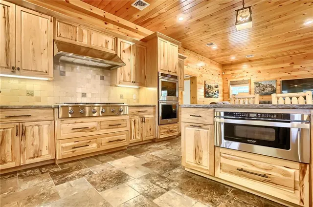 a kitchen with stainless steel appliances kitchen island granite countertop a stove and a refrigerator