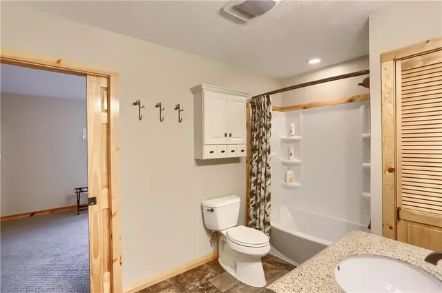 a bathroom with a granite countertop toilet a sink and a shower