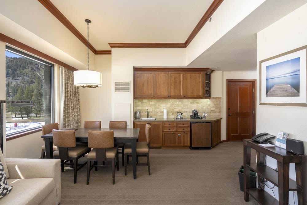 400 Resort Road, Unit 102104106 Olympic Valley, CA 96146 - Photo 6 of 27 a kitchen with stainless steel appliances kitchen island granite countertop a table chairs in it and wooden floors
