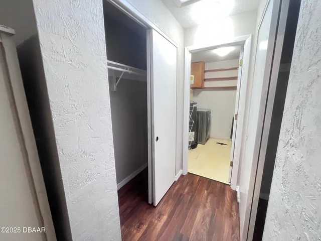 a view of a hallway with wooden floor and closet