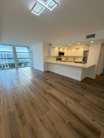 a view of a living room a kitchen island wooden floor and furniture