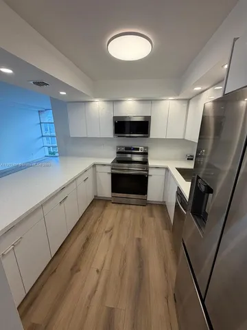 a kitchen with granite countertop a refrigerator stove and sink