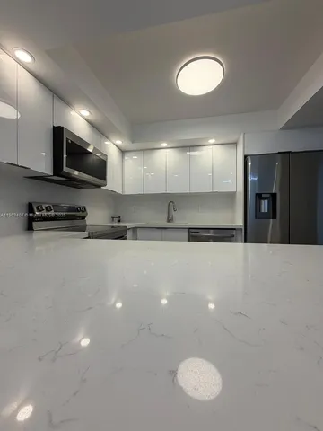 a large kitchen with stainless steel appliances a large counter top