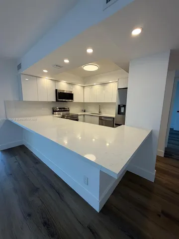 a large kitchen with kitchen island a sink dishwasher a stove and a refrigerator with wooden floor