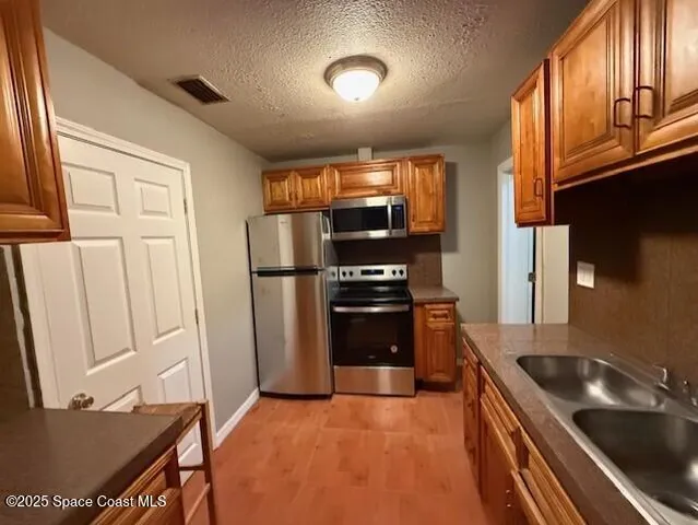 a kitchen with stainless steel appliances granite countertop a refrigerator a stove a microwave and a sink