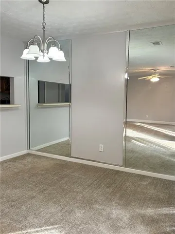 a view of a livingroom with a chandelier fan and windows