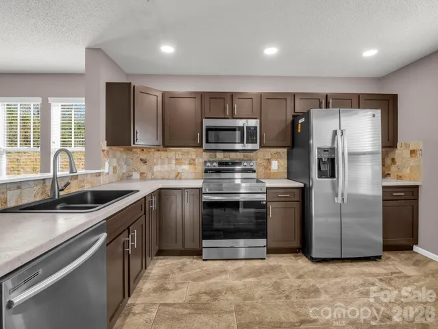 a kitchen with stainless steel appliances granite countertop a sink stove and refrigerator