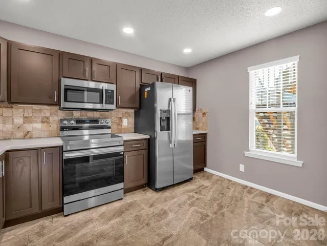 a kitchen with stainless steel appliances granite countertop a refrigerator and a stove top oven