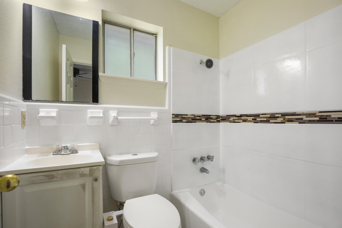 5300 Guadalupe Street, Unit 6202 Austin, TX 78751 - Photo 10 of 10 Bathroom with shower / washtub combination, toilet, tile walls, and vanity