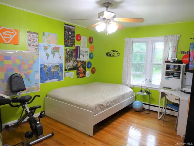 a bedroom with a bed a desk and chair with wooden floor