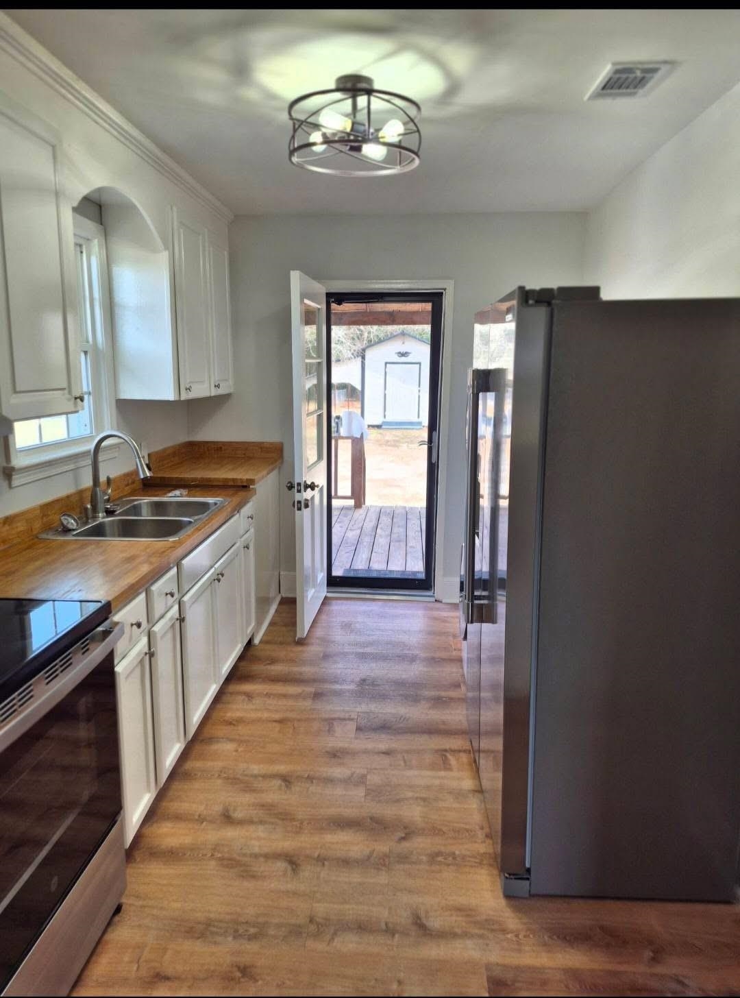 1434 Highway 57 Dillon, SC 29536 - Photo 5 of 9 Kitchen featuring stainless steel appliances, white cabinets, light wood finished floors, and a chandelier