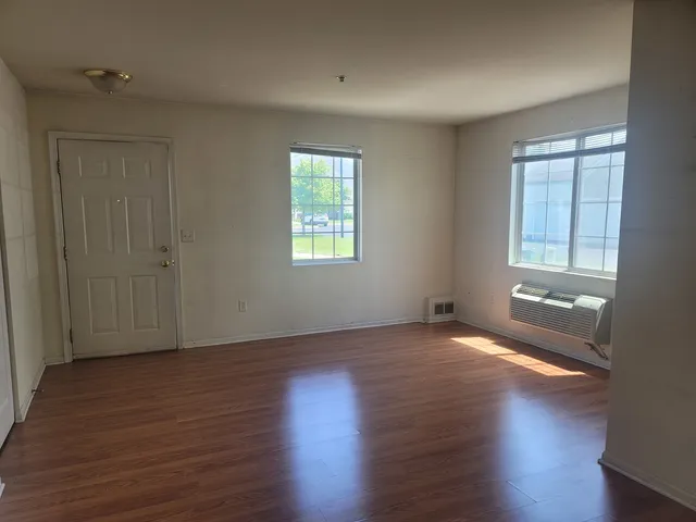 an empty room with wooden floor and windows