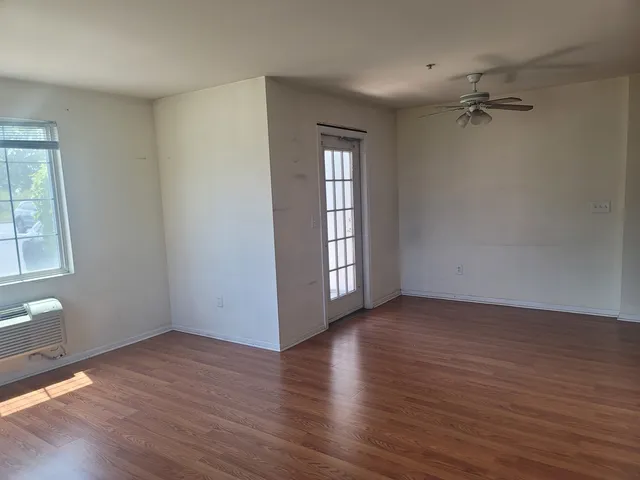 an empty room with wooden floor and windows